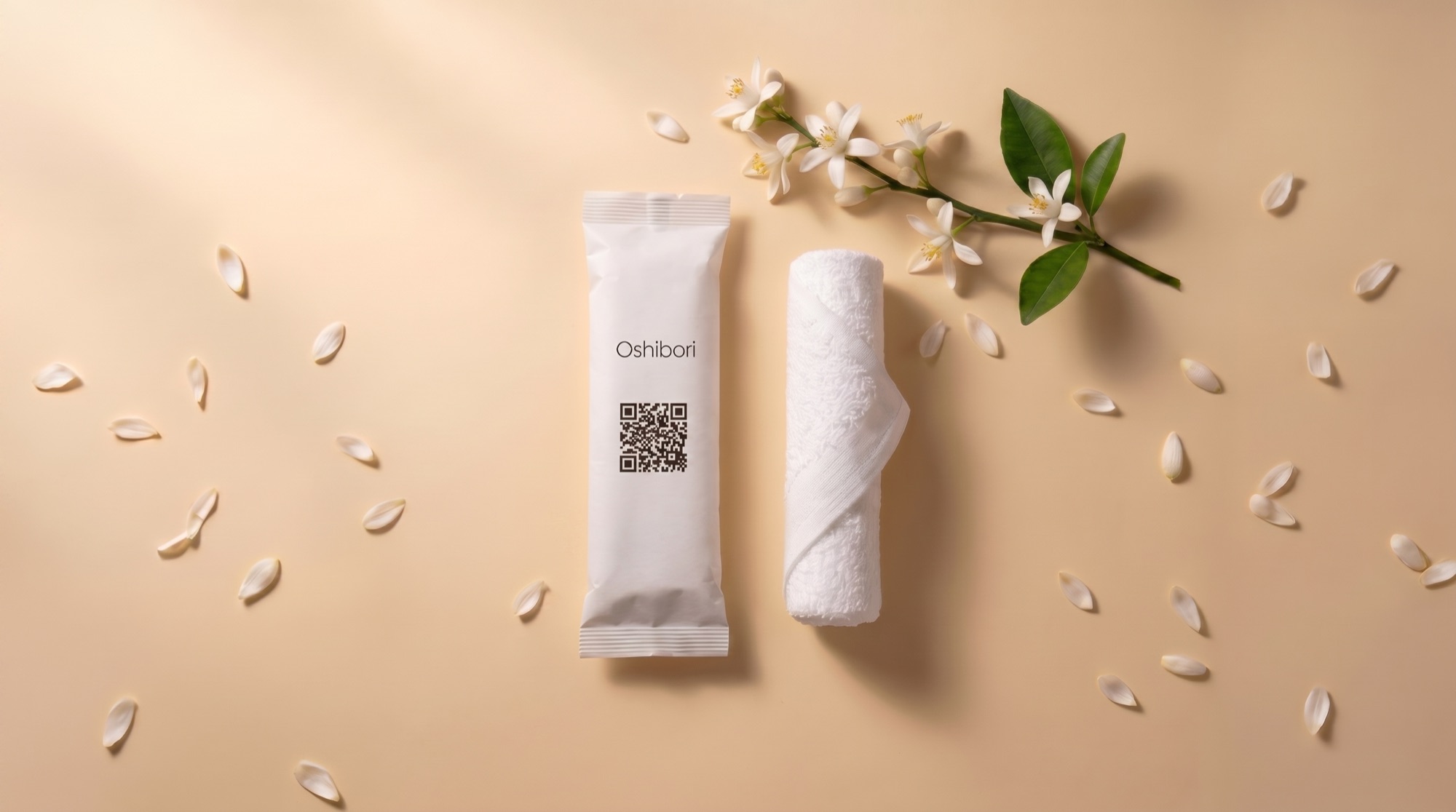 Sachet oshibori Oshibori Media avec QR code, serviette roulée et fleur d'oranger sur fond beige